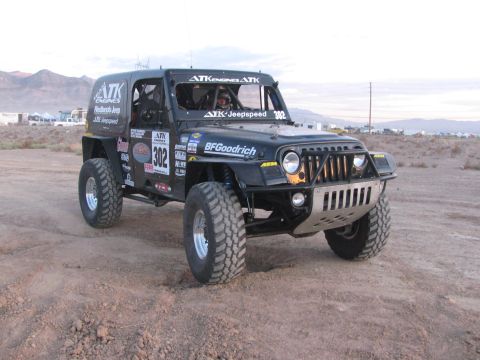 1990 Ford Bronco - black off-road race Jeep marked 302 with ATK Jeepspeed and BFGoodrich graphics staged on a flat desert lot.