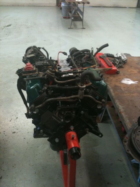 1990 Ford C-150 (Centurion Conversions) - Engine on stand in workshop, with tools on workbench in background.