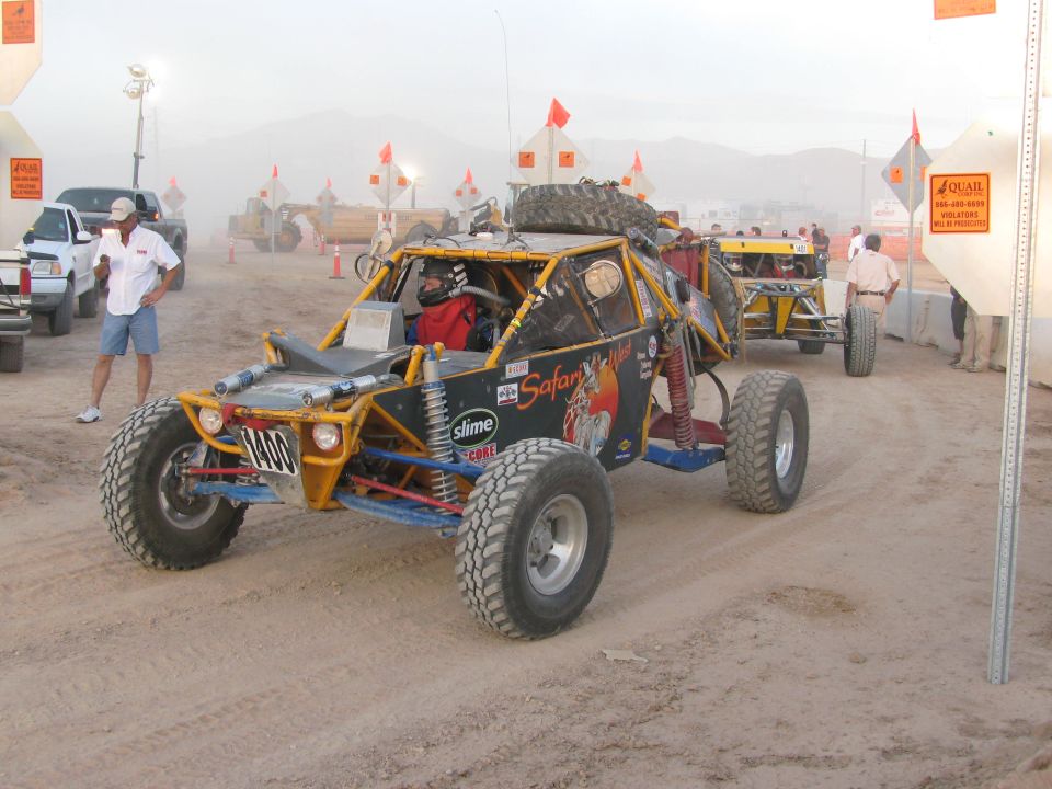 Open tube-frame off-road buggy with Safari Cup graphics carrying spare tire