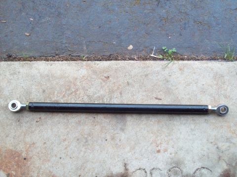 1989 Ford F-150 - A black adjustable linkage rod with silver threaded ends is shown on a concrete and asphalt surface.