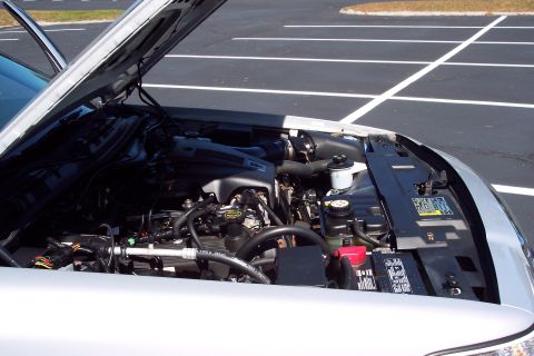 2001 Ford Crown Victoria - Engine bay of a silver Ford Crown Victoria, showing the engine and battery with the hood open.