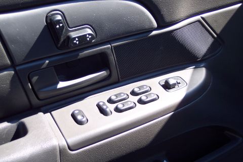 2001 Ford Crown Victoria - Close-up of a car's interior door panel showing the window controls and door handle.