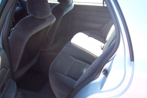 2001 Ford Crown Victoria - The interior of a light blue car, viewed from the rear passenger side, reveals worn grey upholstery on the seats.