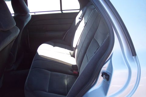 2001 Ford Crown Victoria - The interior of a light blue sedan shows the rear seats and the open passenger door.