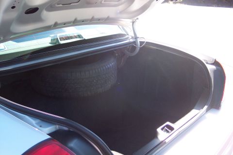 2001 Ford Crown Victoria - The trunk of a car is open, revealing a spare tire and the interior storage area.