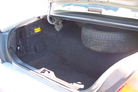 2001 Ford Crown Victoria - The trunk of a car contains a spare tire and a yellow warning sticker.