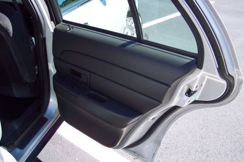 2001 Ford Crown Victoria - Interior view of a car's rear passenger door panel and frame, showing the door handle and window controls.