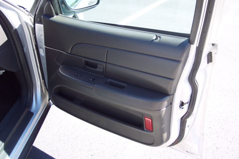 2001 Ford Crown Victoria - Close-up of the interior door panel, showing the black upholstery, window controls, and a red reflector near the bottom.