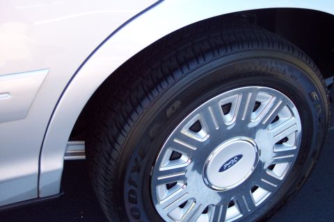 2001 Ford Crown Victoria - Close-up of a silver car's fender and wheel, a Ford logo on the hubcap.