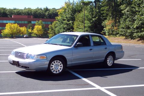 2001 Ford Crown Victoria - A silver sedan is parked in a lot, with trees and a building in the background. The vehicle appears to be a 2003 model.