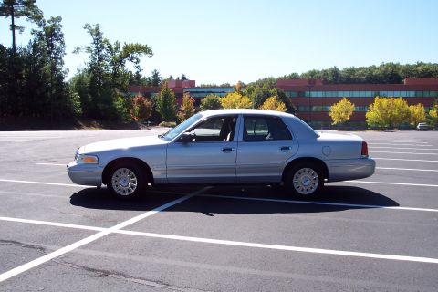 2001 Ford Crown Victoria - Side view of a silver 2001 Ford Crown Victoria parked in a lot on a sunny day.