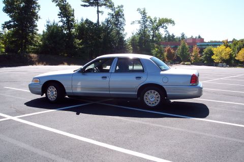 2001 Ford Crown Victoria - A silver 2001 Ford Crown Victoria is parked in an empty lot on a sunny day.