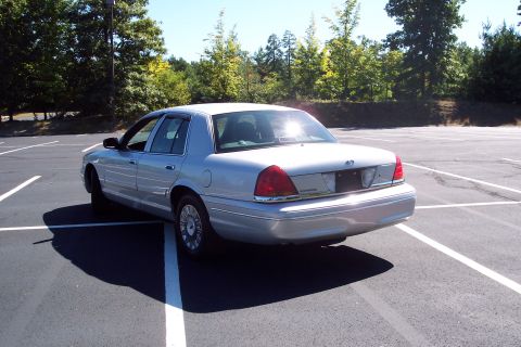 2001 Ford Crown Victoria - Rear view of a silver 2001 Ford Crown Victoria sedan parked in an empty lot.