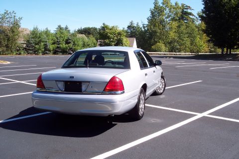 2001 Ford Crown Victoria - A silver 2001 Ford Crown Victoria is parked in an empty lot on a sunny day.