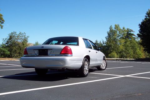 2001 Ford Crown Victoria - Silver sedan parked in a lot under a clear blue sky.