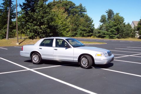 2001 Ford Crown Victoria - Silver 2001 Ford Crown Victoria parked in an empty asphalt lot with trees in the background.
