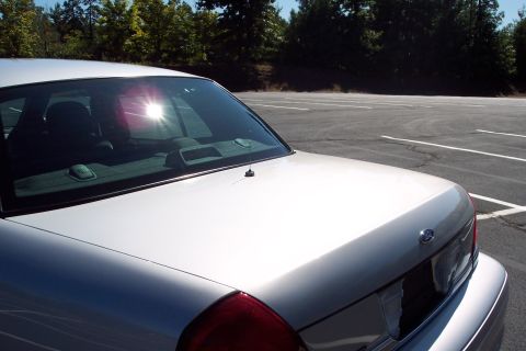 2001 Ford Crown Victoria - Rear view of a silver 2001 Ford Crown Victoria parked in a lot with trees in the background.