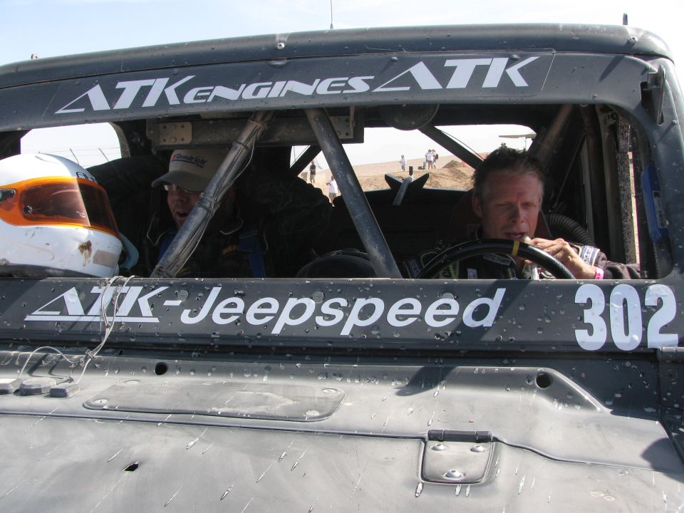 Driver in helmet seated in ATK-Jeepspeed race vehicle number 302