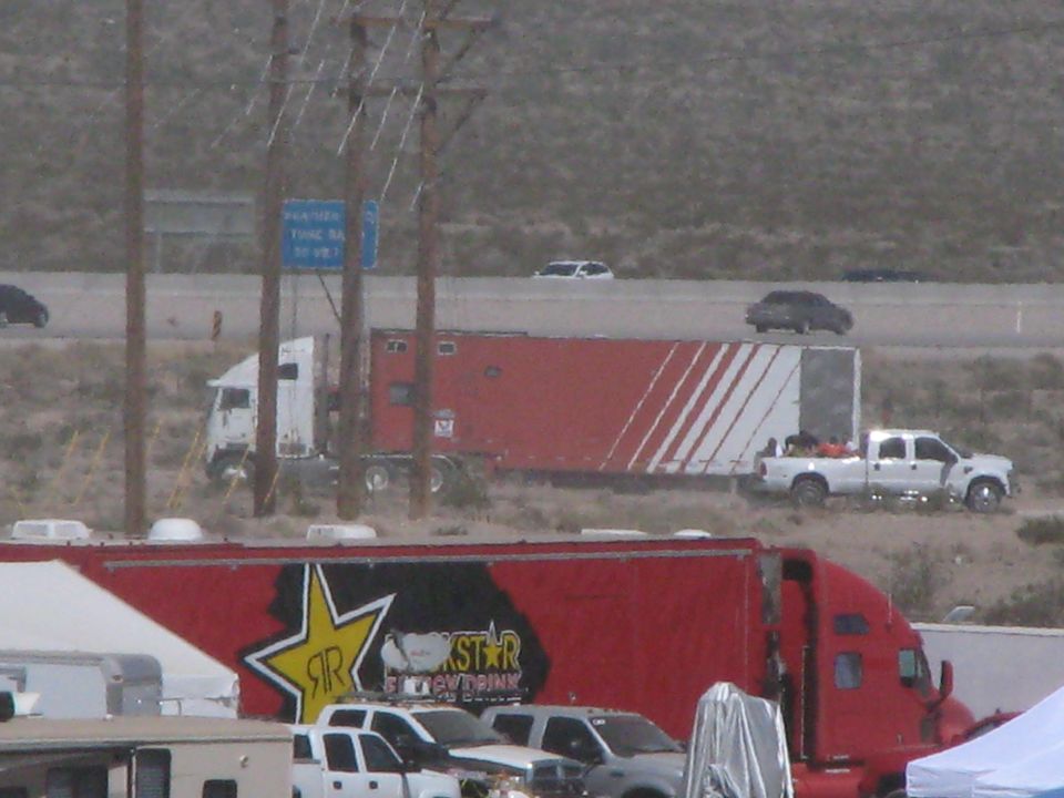 Red and white semi haulers parked near a highway with a Rockstar trailer