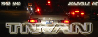 1990 Ford Taurus - Rear view of a 1990 Ford Taurus driving at night with its brake lights illuminated.