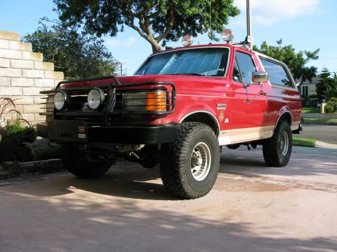 1989 Ford Bronco - This red 1989 Ford Bronco features a prominent bull bar and off-road tires, suggesting it's ready for adventure.