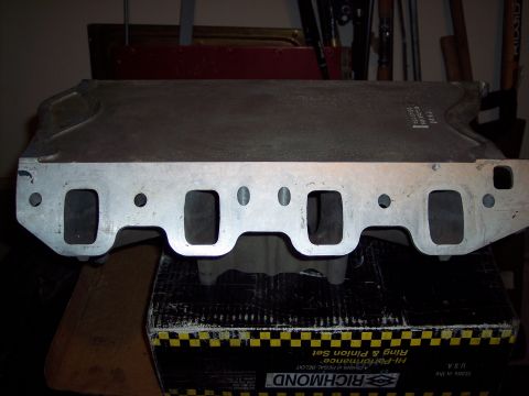 1971 Ford Mustang - An aluminum intake manifold is shown from the side, resting on a box with visible text.