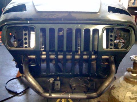 1994 Jeep YJ - Front view of a Jeep YJ with a custom roll cage and missing headlights.