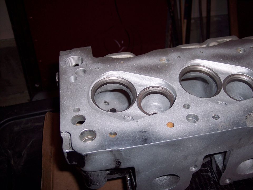 Close-up of an engine cylinder head with visible valve openings and bolt holes