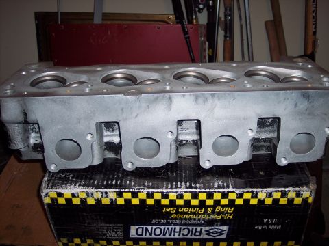 1971 Ford Mustang - An engine cylinder head sits atop a box of automotive parts, with no clear indication of vehicle year or make.
