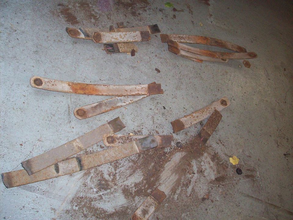 Several rusty leaf springs scattered on a concrete floor