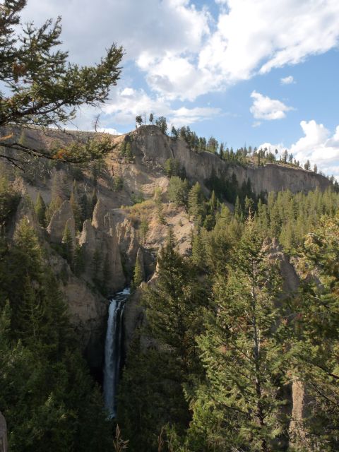 2006 Ford E350 - A tall waterfall plunges into a narrow canyon, framed by cliffs and dense evergreen trees.