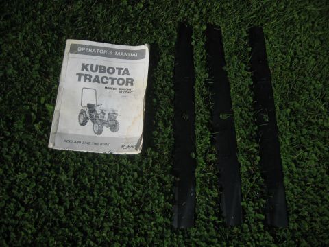 1993 Ford Probe - An operator's manual for a Kubota tractor and three mower blades are laid out on a grassy surface.