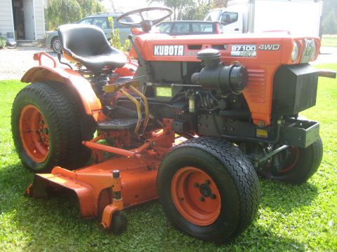 1993 Ford Probe - Orange Kubota B7100 4WD tractor with a mower deck attached, parked on grass.