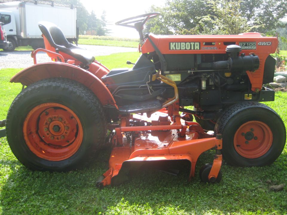 Orange Kubota tractor with a mower deck, viewed from the side