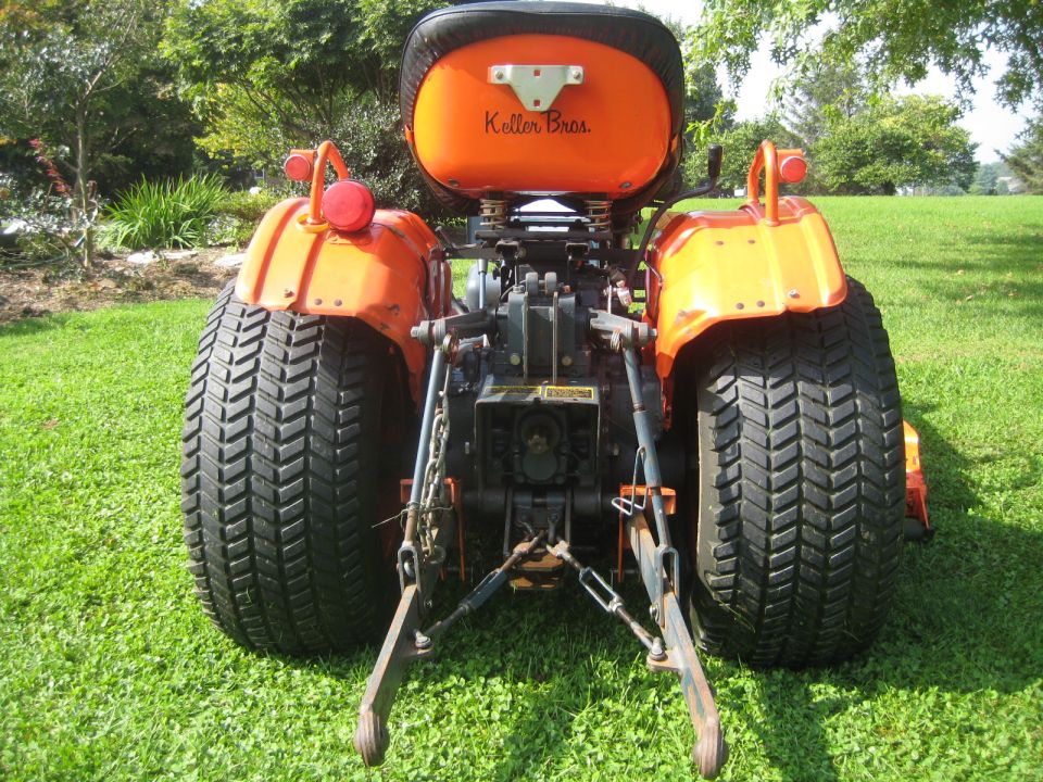 Rear view of an orange tractor with large tires and "Keller Bros." on the seat