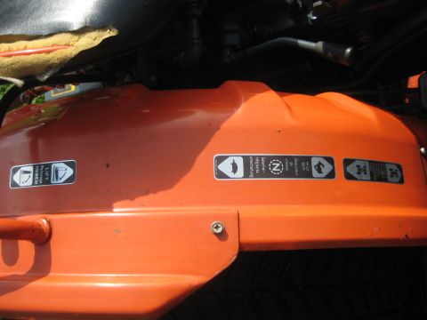 1993 Ford Probe - Close-up of an orange lawn mower deck showing various safety decals and warning symbols.