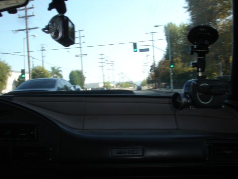 1993 Ford Taurus - Interior view of a vehicle's dashboard, showing two camera mounts attached to the windshield and rearview mirror.
