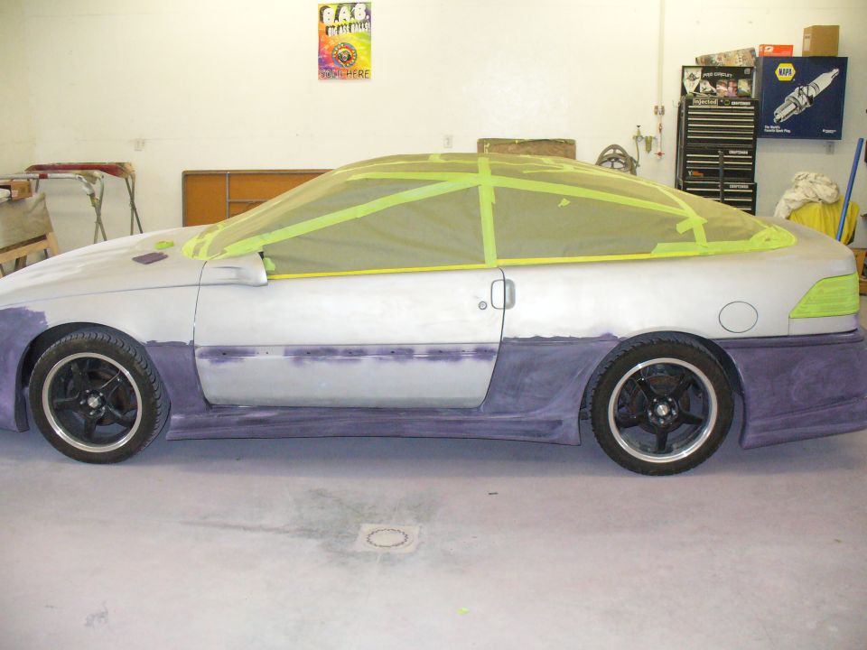 Silver and purple coupe in body shop with masked windows