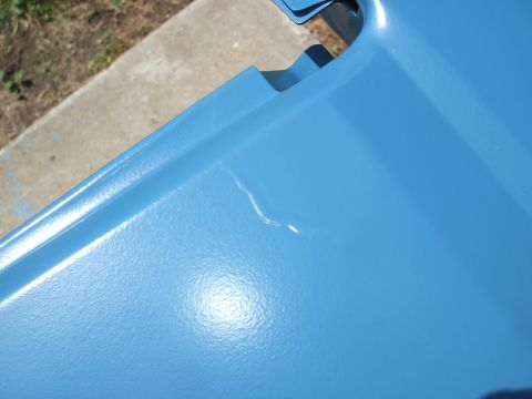 1990 Ford Bronco - A close-up of a blue painted metal panel shows a dent and a watermark from Supermotors.net.