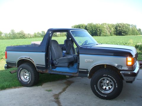 1990 Ford Bronco - This 1990 Ford Bronco is shown from the side with both doors open, revealing the interior and blue carpeting.