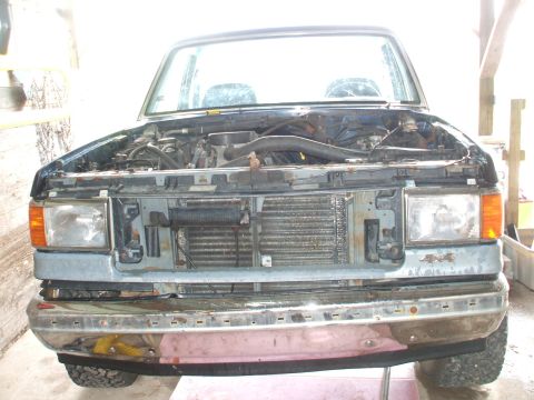 1990 Ford Bronco - Front view of a blue SUV with its hood open, revealing the engine and radiator components.