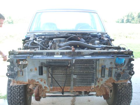 1990 Ford Bronco - A 1990 Ford Bronco's front end is disassembled, revealing the engine and rusty components.