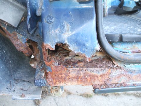 1990 Ford Bronco - Severe rust damage to the door sill area of a blue vehicle.