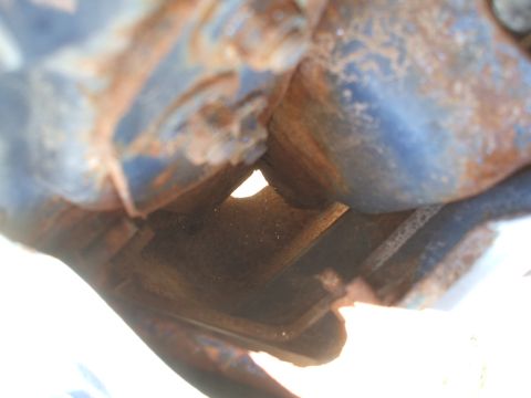 1990 Ford Bronco - This image shows heavily rusted metal parts with blue paint remnants, suggesting a part of a vehicle's chassis or engine bay.