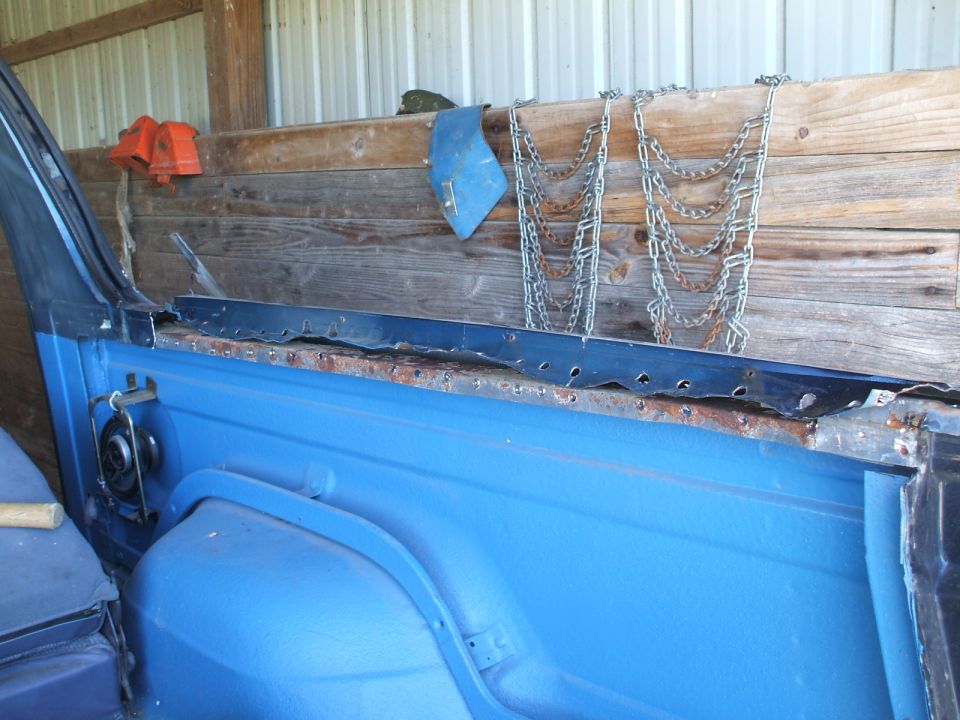 Blue vehicle interior showing rusted metal trim and a wooden wall with chains