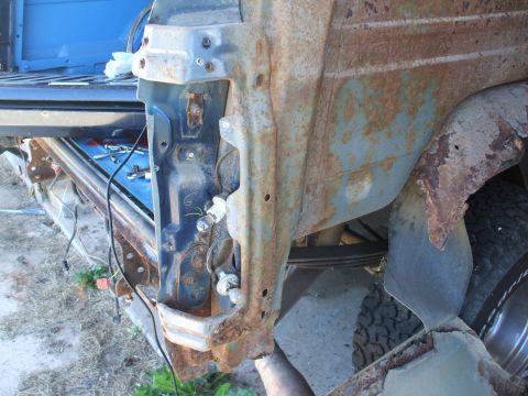 1990 Ford Bronco - Close-up of heavily rusted vehicle bodywork, showing exposed metal and wiring.