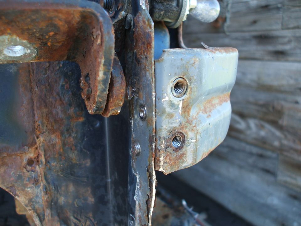 Rusted metal bracket with bolts, Supermotors.net logo visible