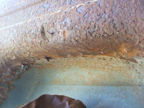 1990 Ford Bronco - Close-up view of severe rust damage on a vehicle's undercarriage or body panel.
