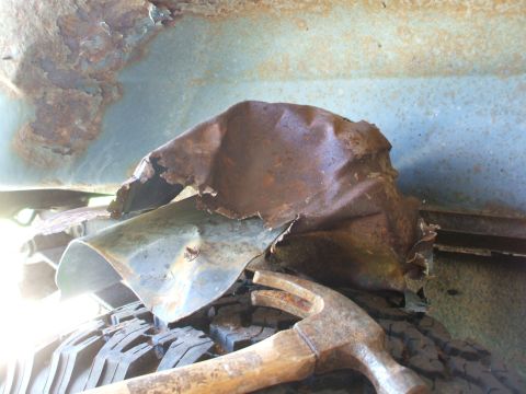 1990 Ford Bronco - Close-up of heavily rusted metal debris and a hammer resting on a tire.