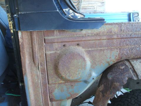 1990 Ford Bronco - Close-up of a heavily rusted vehicle body panel, showing signs of wear and tear.